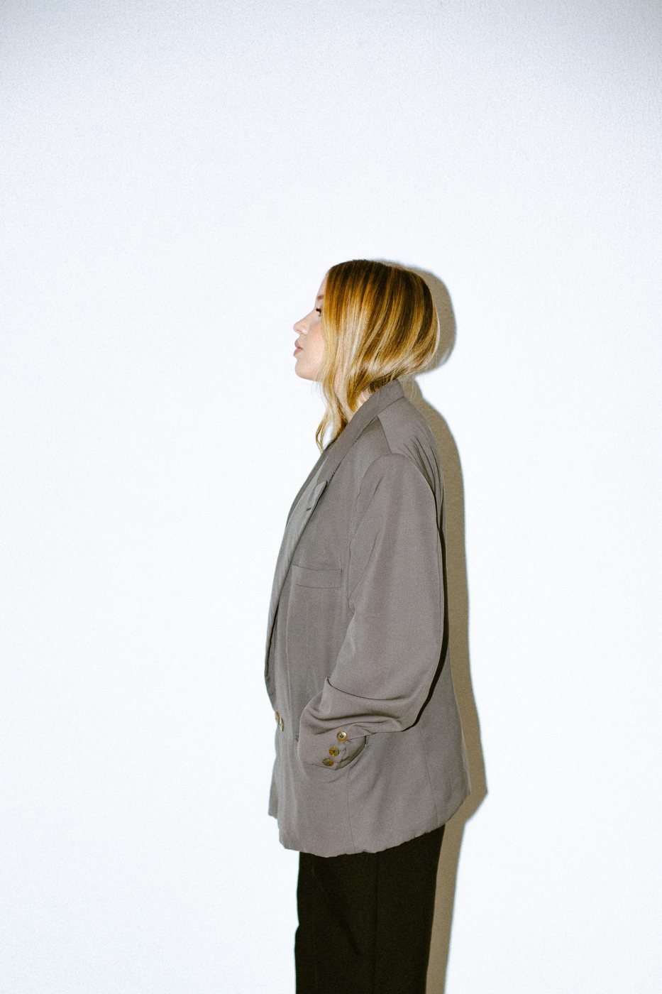 Retrato de perfil, blazer cinza em fundo claro